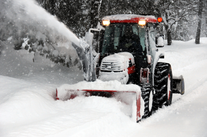 Red Snow Blowing Tractor Removing Snow from a Driveway